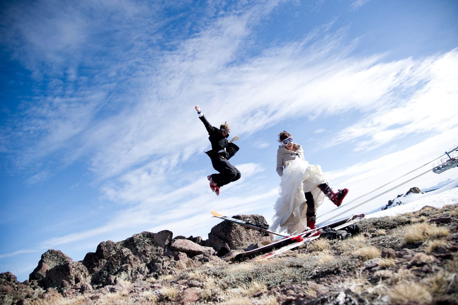 Chipeta-Lodge_Bride-groom-ski-summit - Chipeta Lodge Resort + Spa Bride and Groom in wedding outfits plus ski boots celebrating on a rocky summit near Chipeta Lodge Resort + Spa