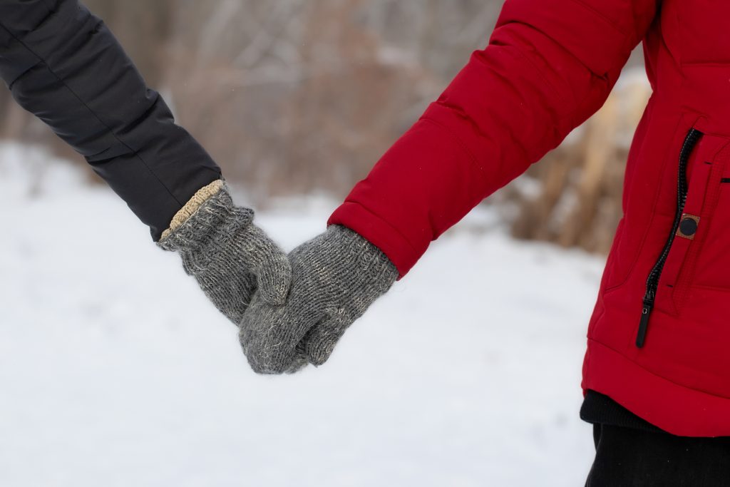 Man and woman in warm clothes holding hands close-up - Chipeta Lodge Resort + Spa Handholding with mittens in the snow near Chipeta Lodge Resort + Spa