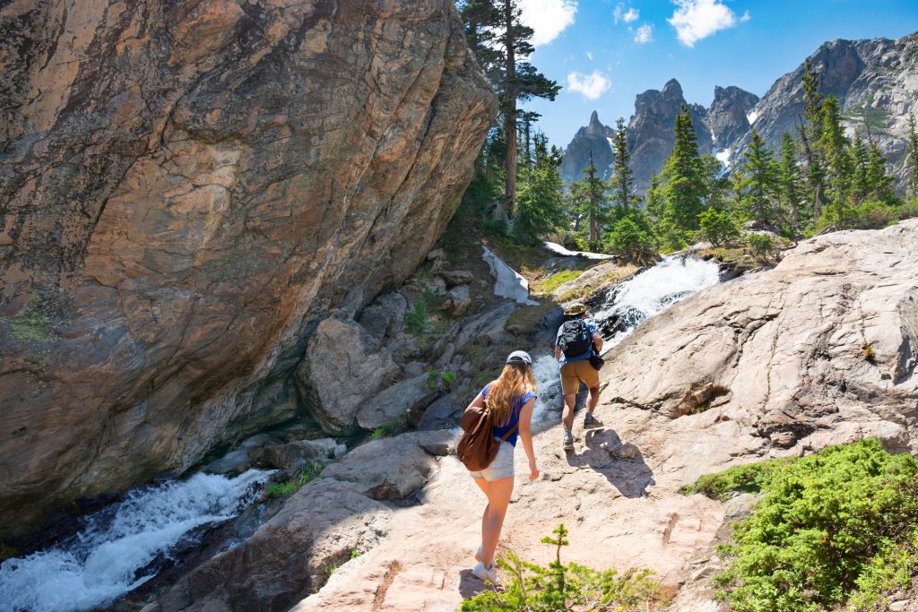 Couple hiking by water falls on river in mountains near Chipeta Lodge Resort + Spa