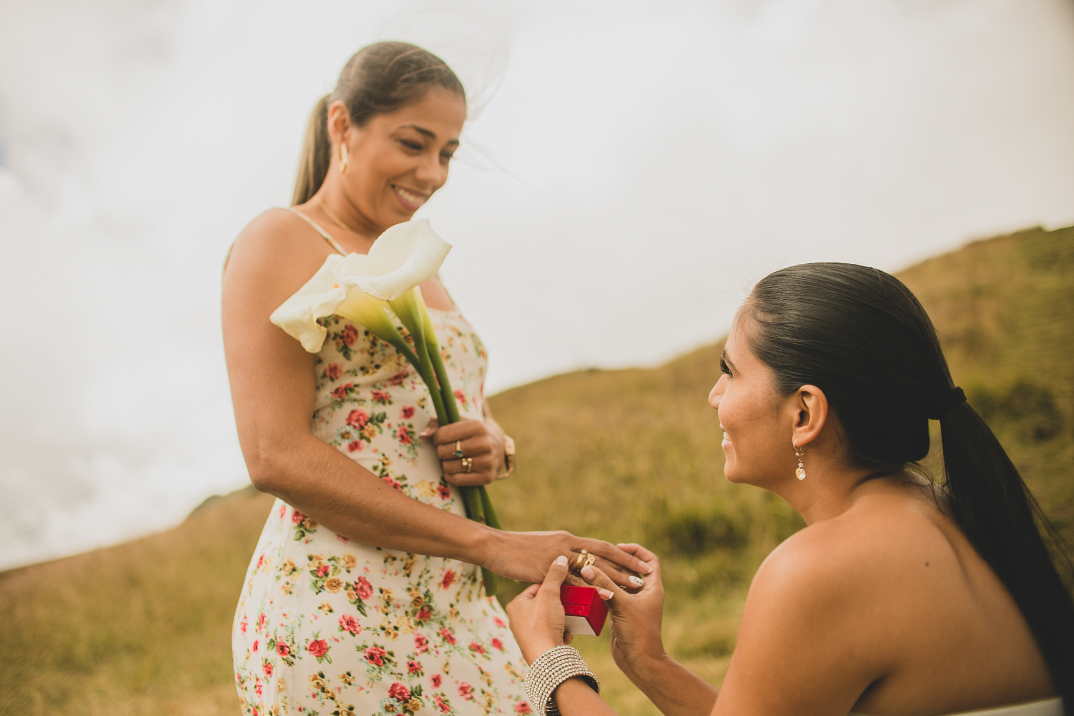 portrait of two beautiful women outdoors making a marriage proposal while one holds a beautiful flower and smiling happily - Chipeta Lodge Resort + Spa A couple exchanging rings on the mountain near Chipeta Lodge Resort + Spa